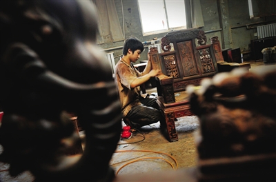 工人正在制作红酸枝家具，红酸枝制品的投资属性被业内看好。